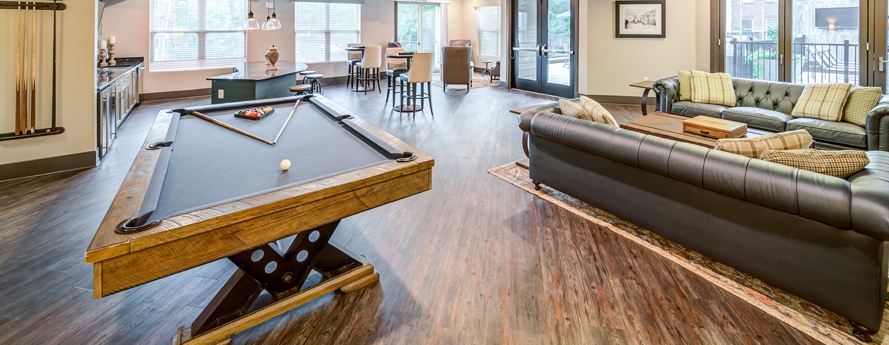 Spacious and well lit game room with billiard table and large windows 